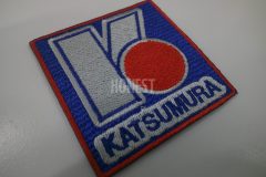 青色の生地にグレーと青と赤糸で会社ロゴを刺繡した、オリジナル刺繡ワッペンの制作事例。