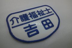 白色の生地に青色の糸で職種名と名前を二段で刺繡した、オリジナル刺繡ワッペンの制作事例。