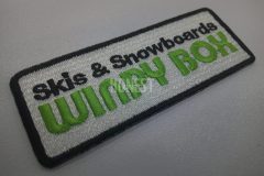 白色の生地に黒でグッズ名を黄緑で店舗名を刺繡した、レンタルショップのオリジナル刺繡ワッペンの制作事例。