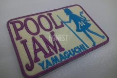 クリーム色の生地に紫色で店名と水色でビリヤードのキューを持った女の子のイラストを刺繡した、オリジナル刺繡ワッペンの制作事例。