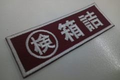 赤のえんじ色の生地に、白糸で担当部署名をゴシック体で刺繍した、もったいないワッペン。