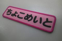 ピンクのアーバンツイル生地に黒糸で文字を刺繍。外周フチは派手なショッキングピンクで仕上げた、もったいないワッペン。
