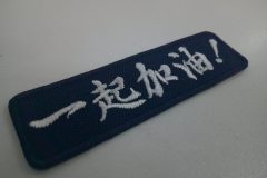濃紺の生地に「一起加油！」と応援メッセージを白糸で刺繍した、もったいないワッペンの制作事例。