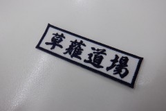 白のツイル生地に道場名を刺繍。文字とフチ、どちらも濃紺の糸で仕上げた、もったいないワッペン。書体は行書体。
