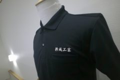 黒ポロシャツの左胸に銀糸で漢字で企業名を刺繡した制作事例。