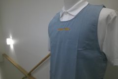 水色のエプロンの胸元中央部分に保育園名を英字でネーム刺繡した制作事例。