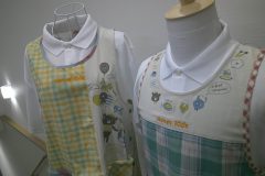 2つのエプロンの胸元中央部分それぞれに子ども関連の施設のロゴを刺繡した制作事例。