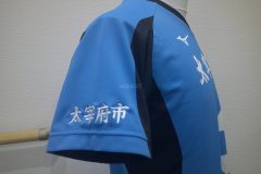 ブルー色のバレーボールユニフォームシャツの右袖に白糸で地域名を刺繍した制作事例。