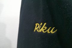 お持ち込みのパーカー左袖に個人名を金糸でネーム刺繍した作品。使用した書体はeasy script。