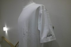 白Tシャツの左袖に漢字の企業名を黒糸で刺繡した制作事例。