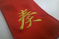 帯に刺繡加工した制作事例。赤地×金のアップ。
