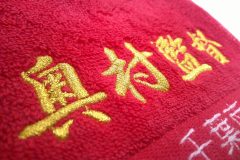 お持ち込みの赤のタオルに空手道場の監督名を煌びやかな金糸でネーム刺繍した作品。