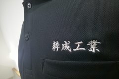 黒ポロシャツの左胸に銀糸で企業名を刺繡した制作事例のアップ。