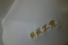 白Tシャツの左胸に銀糸で企業名を刺繡した制作事例のアップ。