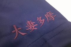 紺色のTシャツに紫の糸色で学校名を左袖に刺繡した制作事例のアップ。
