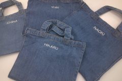 デニム素材のトートバッグ4つにそれぞれ白糸で個人名を刺繡した制作事例。