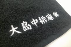 お持ち込みの黒のハンドタオルにチーム名を刺繍した部分のアップ。