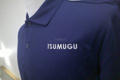 紺色のポロシャツの左胸に介護福祉施設名を白糸で刺繡した制作事例のアップ。