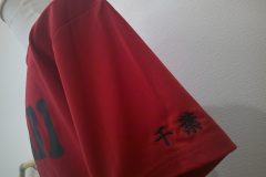 赤のドライTシャツの左袖口に黒糸で県名を刺繍した制作事例。書体は楷書体を使用。