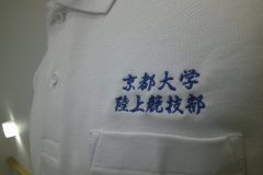 白のポロシャツ左胸に青糸で学校名と部活動名を刺繡した制作事例のアップ。