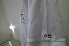 白いポロシャツの左袖に黒糸で個人名の刺繍をした制作事例。