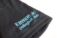 黒Tシャツの左袖にクラブチーム名をターコイズブルーの糸で刺繡した制作事例。