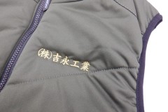 グレーのお持ち込みのダウンベストの左胸に金糸で企業名を刺繡した制作事例。