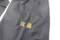 黒のウィンドブレーカーの左袖に金糸で個人名を刺繍した制作事例。書体は楷書体を使用。