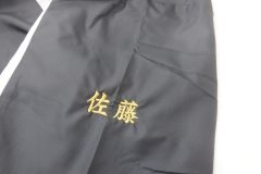 黒のウィンドブレーカーの左袖に金糸で個人名を刺繍した制作事例。書体は楷書体を使用。