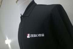 黒いポロシャツの左胸に『ZERO 警備』のロゴ。赤と白の四角いシンボルの横に白文字で社名が入ったフルカラー転写プリントの制作見本のアップ。
