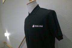 黒いポロシャツの左胸に『ZERO 警備』のロゴ。赤と白の四角いシンボルの横に白文字で社名が入ったフルカラー転写プリントの制作見本。