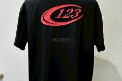 黒いTシャツの背中中央にに赤いシートで社名マークをプリントしたラバープリントの制作実績。全体を表示。