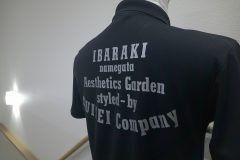 黒いドライTシャツの背中全面にメタリックシルバーのシートで社名ロゴと所在地、業務内容などを表す文字をデザインした、ラバープリントの制作実績。