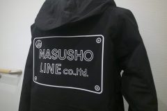 黒いフード付きジャケットに白いシートで社名でデザインしたマークをプリントしたラバープリントの制作実績。
