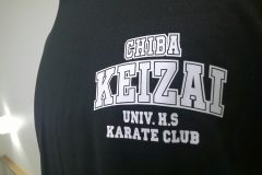 黒いTシャツの左胸に白いシートで学校名と部活名のエンブレムマークをプリントしたラバープリント部分のアップ。