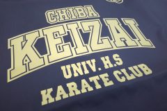黒いナップザックにメタリックゴールドのシートで、学校名、部活名のエンブレム、シンボルマークのワンポイントがデザインされたラバープリント部分のアップ。