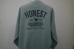 ミントグレーのトレーナーの背中全面に黒いシートで大きく「Honest」のロゴを配置したラバープリントの制作見本。