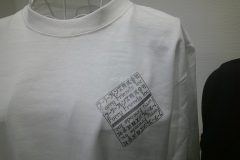 白いロングTシャツの左胸にグリッターシルバーのシートで社名を用いてデザインされたマークをプリントしたラバープリントの制作実績。