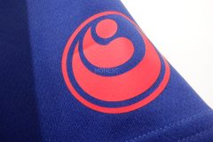 青いドライTシャツの左袖に赤いシートで道場の紋章をプリントしたラバープリント部分のアップ。