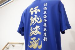 青いドライTシャツの背中全面にメタリックゴールドのシートで、道場理念が躍動感ある筆文字で縦に大きくデザインされており、その横に白いシートで道場支部名がプリントされたラバープリントの制作実績。