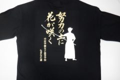 黒いドライTシャツの背中全面に白いシートで人物のシルエット、メタリックゴールドのシートで教育理念と学校名、部活名をプリントしたラバープリントの制作実績。シートを重ねてプリント圧着することで奥行きを表現している。