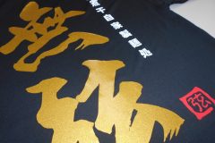 黒いTシャツの背中全面にグリッターゴールドのシートで大きく躍動感ある筆文字でデザインしたラバープリント部分のアップ。