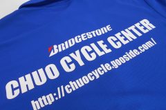 ブルーのドライポロシャツの背中に自転車販売店のロゴを、ホワイト・レッドの2トーンで加工したラバープリントの制作事例。