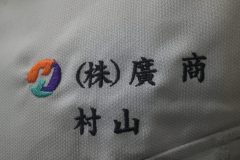 シルバーグレーのワークシャツ左胸に会社名と個人名を二段構成で刺繍をした制作実績のアップ。