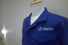 お持ち込みの作業服の左胸に、白糸でサテン縫いをメインに会社名を刺繍した制作事例。
