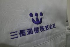 作業服の左胸に企業ロゴと社名を二段で刺繍加工した、オリジナル刺繍の制作事例のアップ。