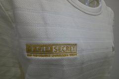 白のTシャツの右胸にメタリック金糸で自動車メーカーのロゴを刺繍した、オリジナル刺繍の制作事例のアップ。