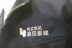作業服の左胸に建設会社のロゴ文字を白糸にて刺繍をした、制作事例のアップ。