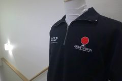 お持ち込みのハーフジップスウェットの左胸に所属団体のロゴを白糸と赤糸で刺繍した制作事例。