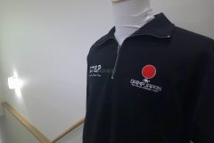 お持ち込みのハーフジップスウェットの左胸に所属団体のロゴを白糸と赤糸で刺繍した制作事例。